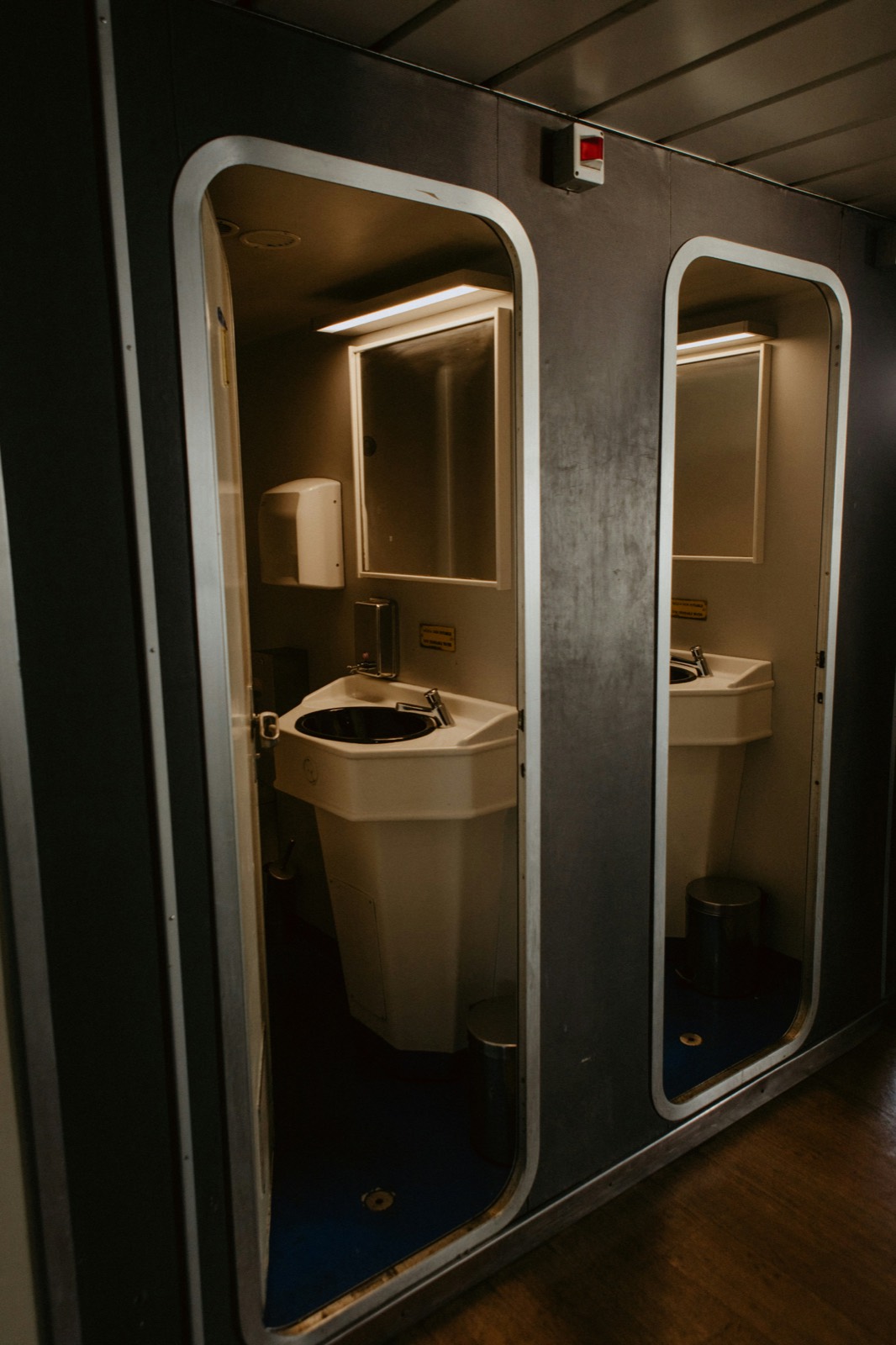 Restroom trailer interior with sink, mirror and lit cubicle
